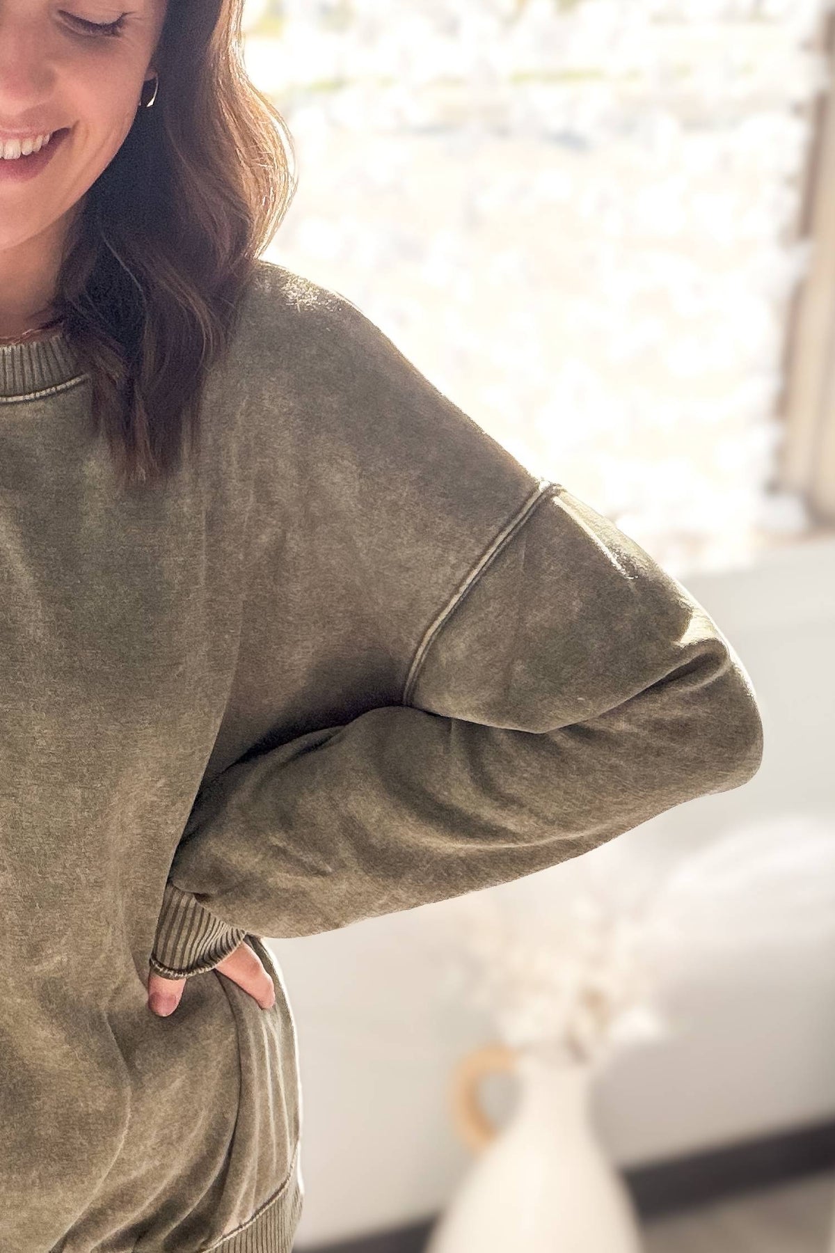Person wearing a olive sweatshirt with a blurred background