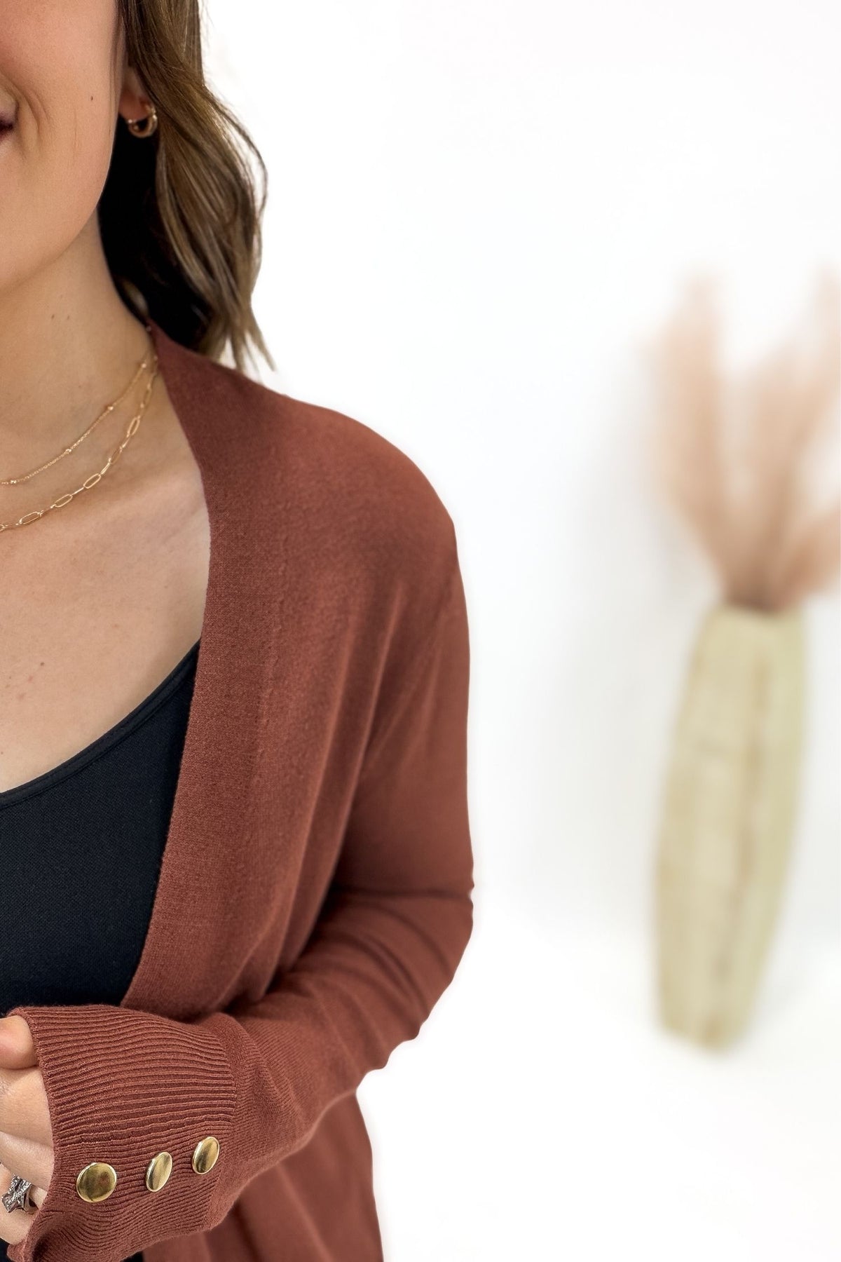 Copper cardigan with gold buttons worn by a person on a white background