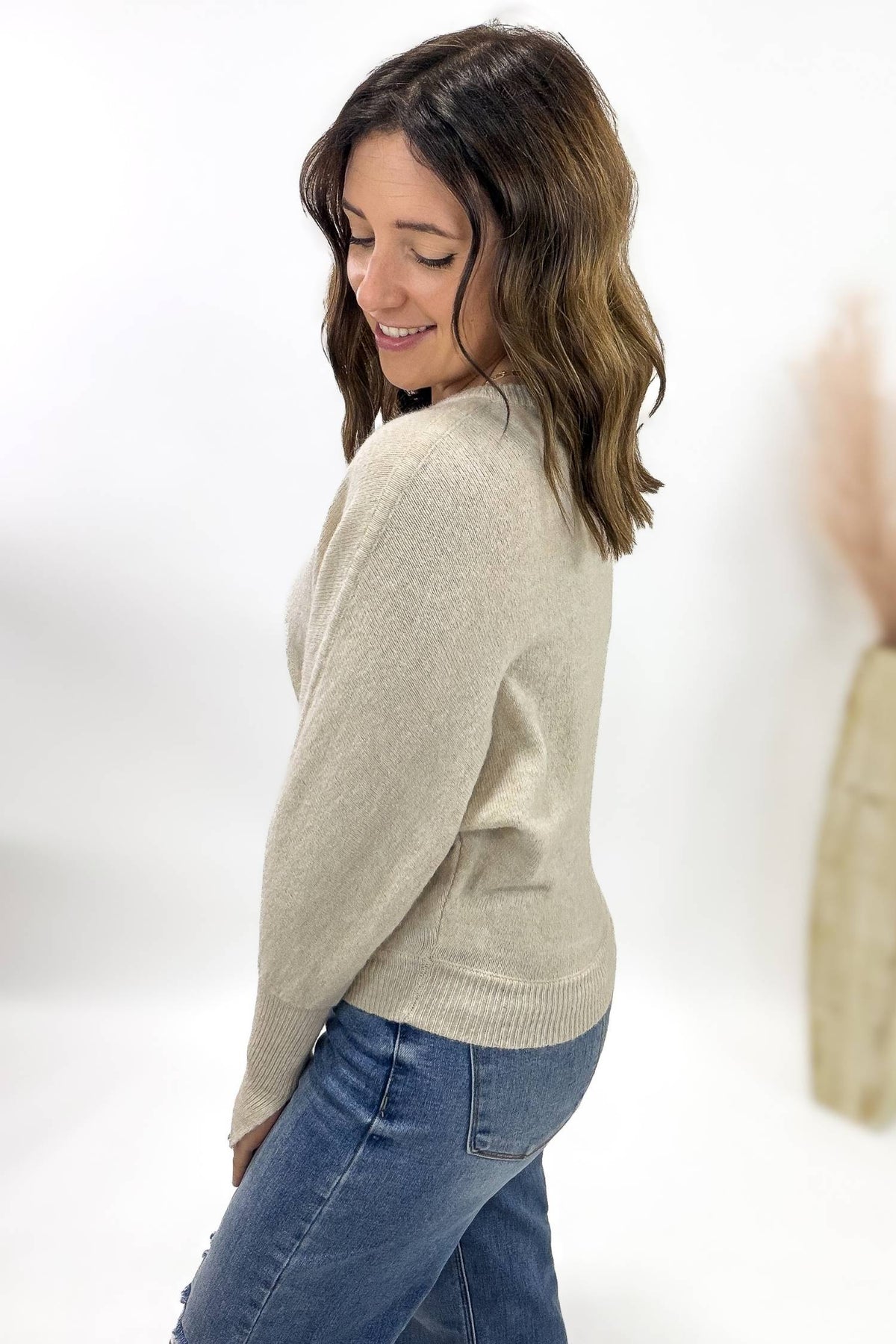 Woman wearing a beige sweater and blue jeans on a white background