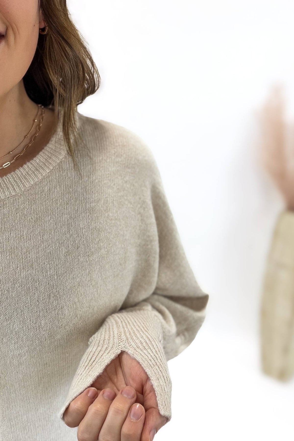 Person wearing a beige sweater with a blurred background