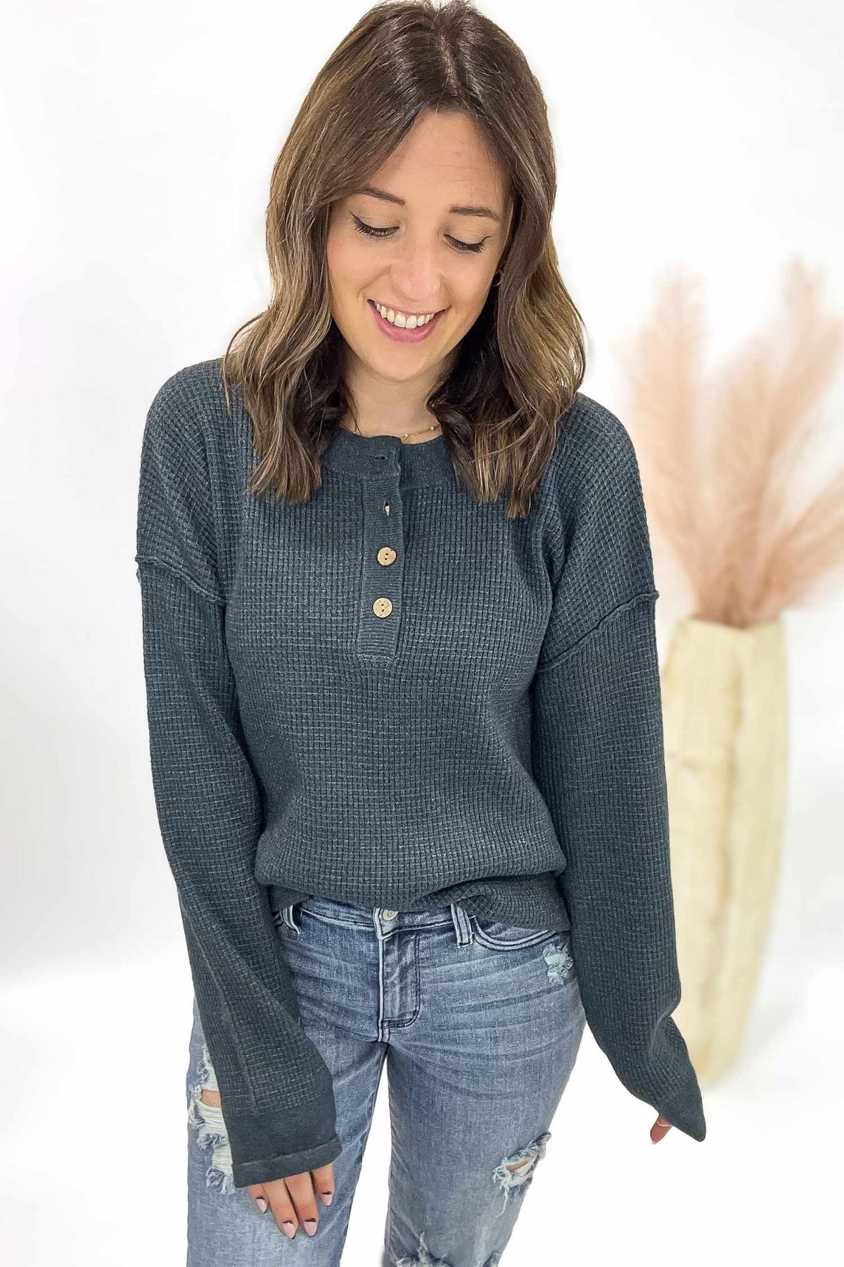 Woman wearing a dark blue long-sleeve shirt and jeans against a white background