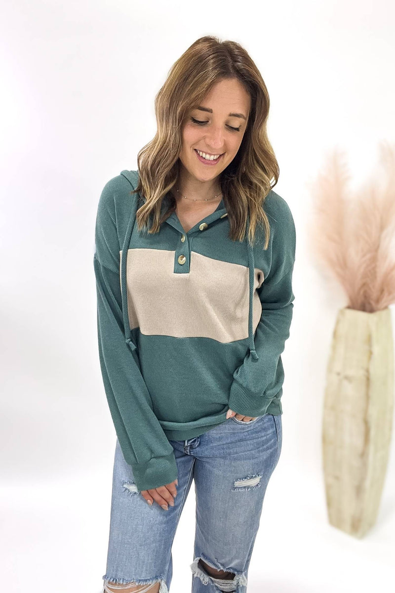 Woman wearing a green and beige long-sleeve shirt with ripped jeans on a white background