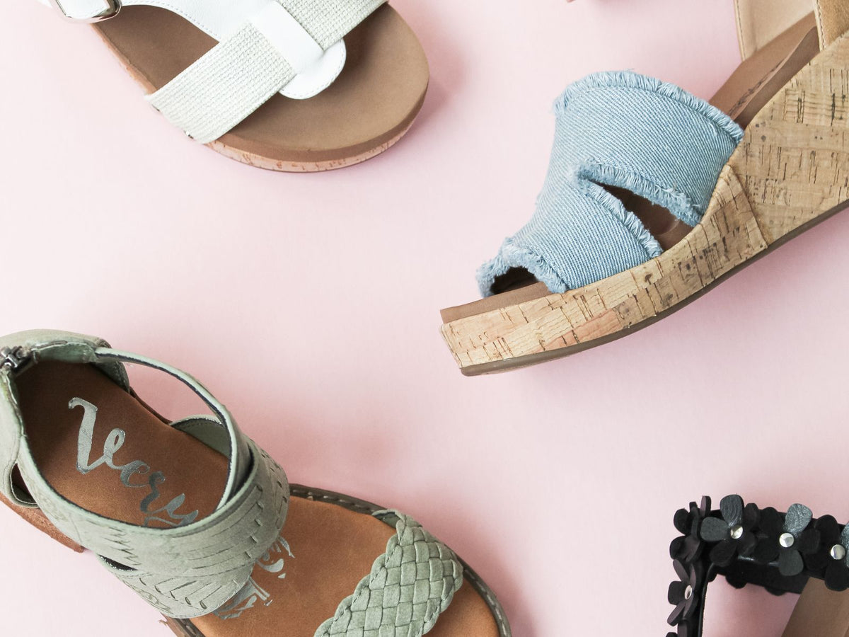 Four pairs of women's sandals on a pink background