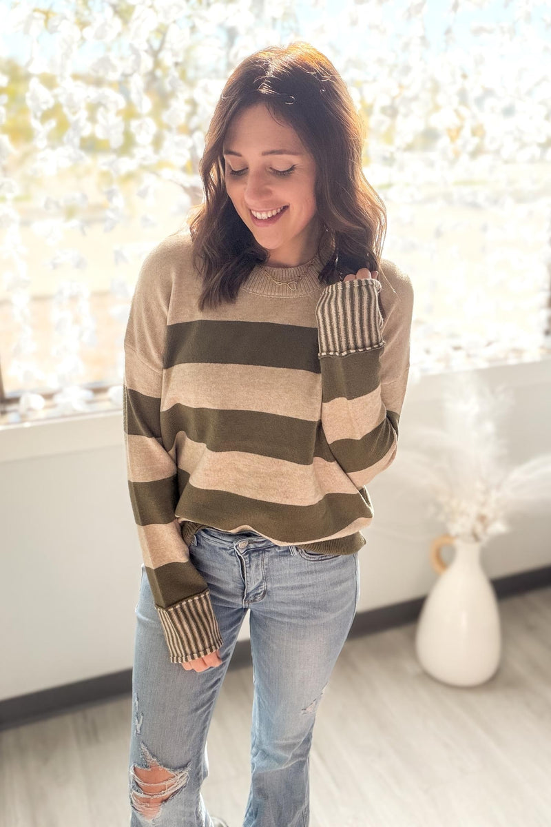 Woman wearing a striped sweater and jeans in a bright room.
