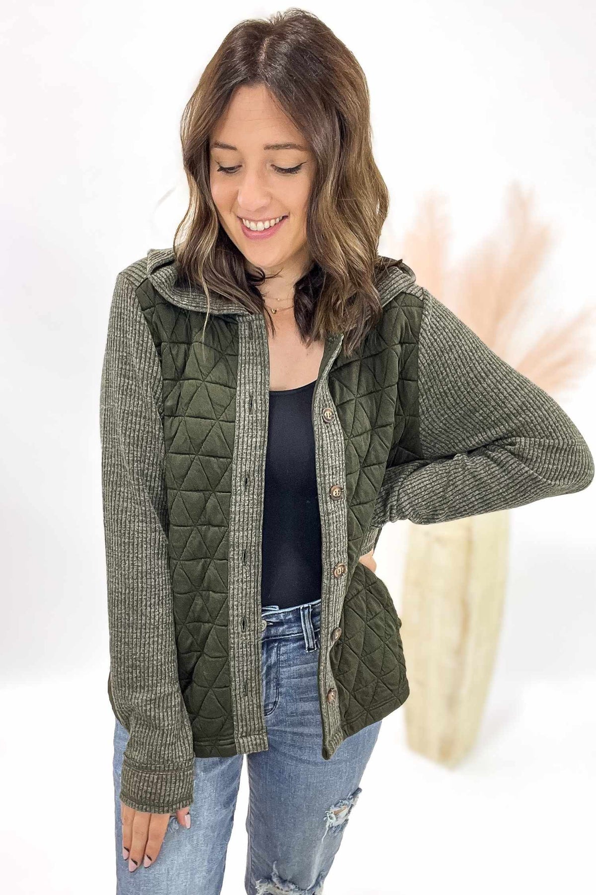Woman wearing a green quilted jacket with a white background