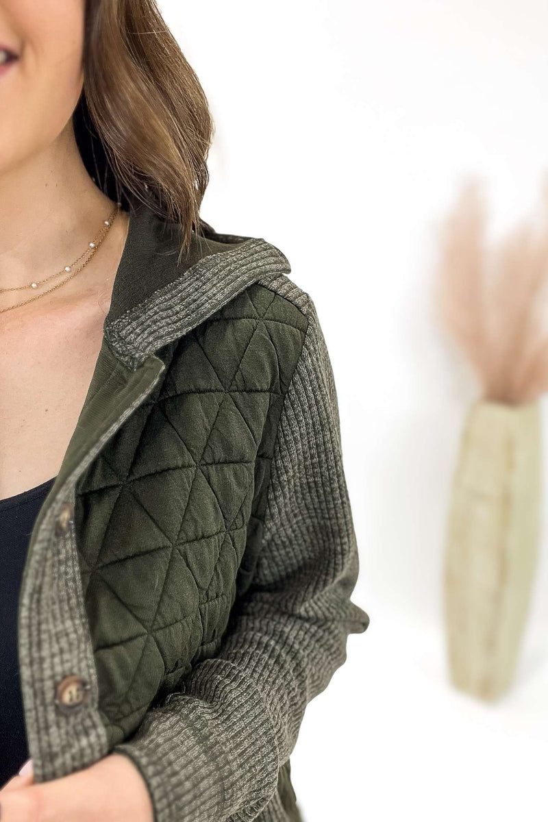 Person wearing a green quilted button up on a white background
