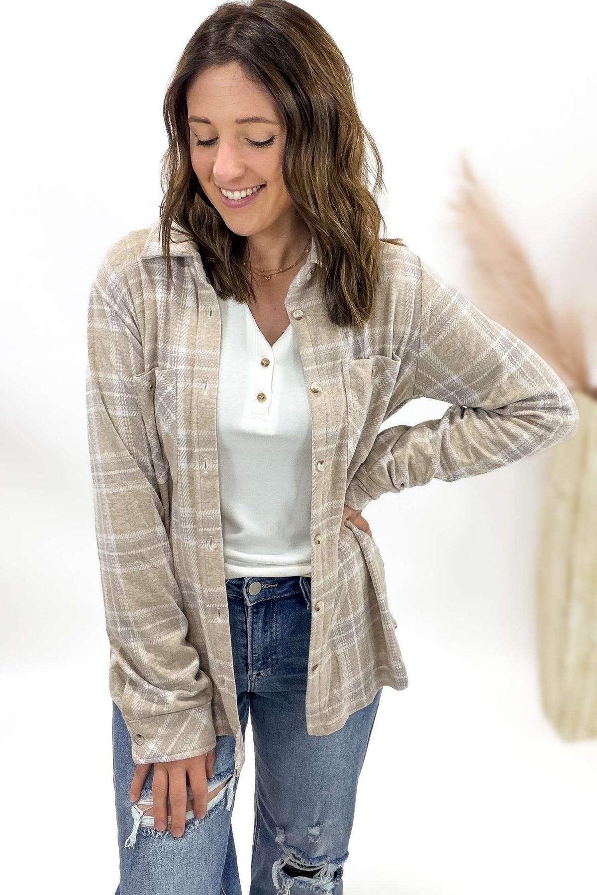 Woman wearing a plaid shirt over a white top and jeans on a white background