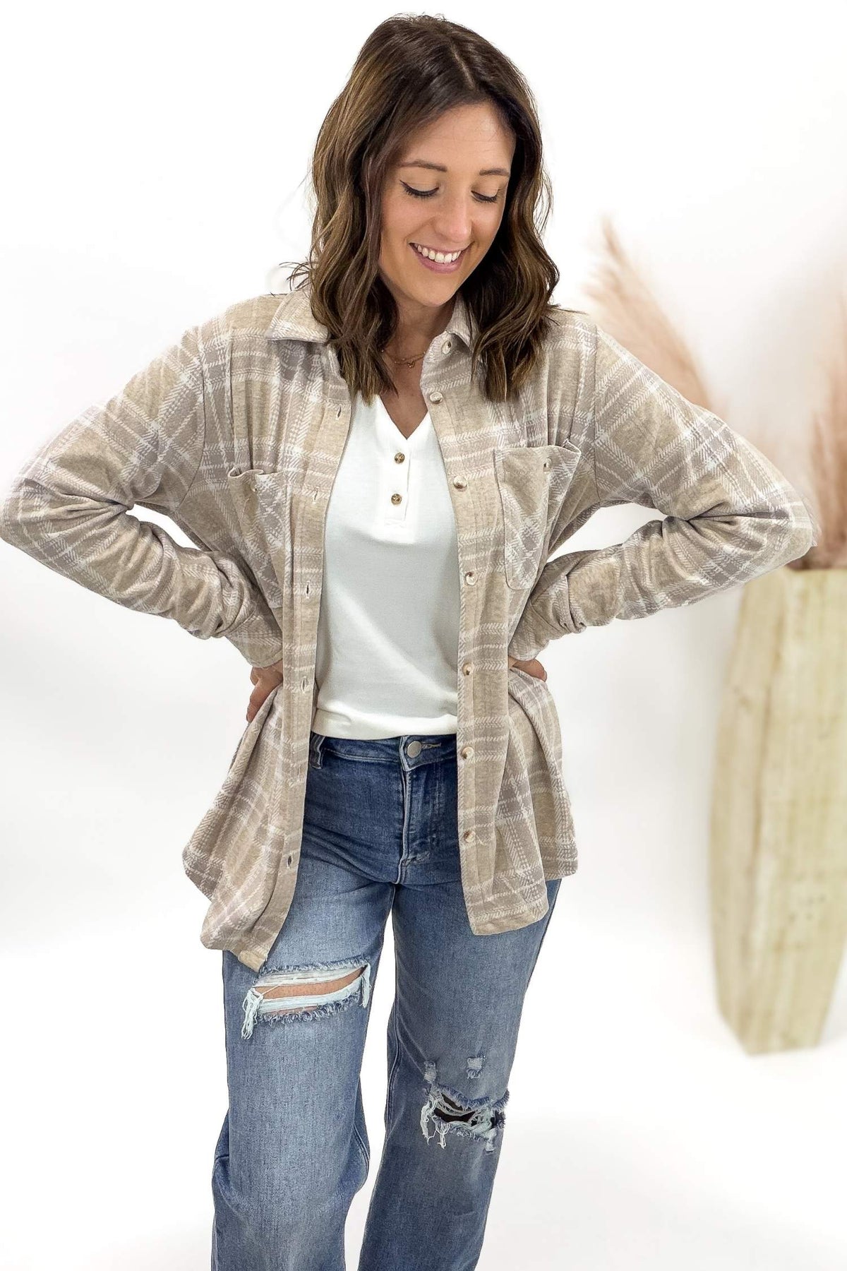 Woman wearing a plaid shirt over a white top and jeans on a white background