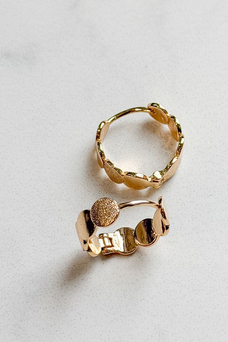 Two gold hoop earrings on a light gray background