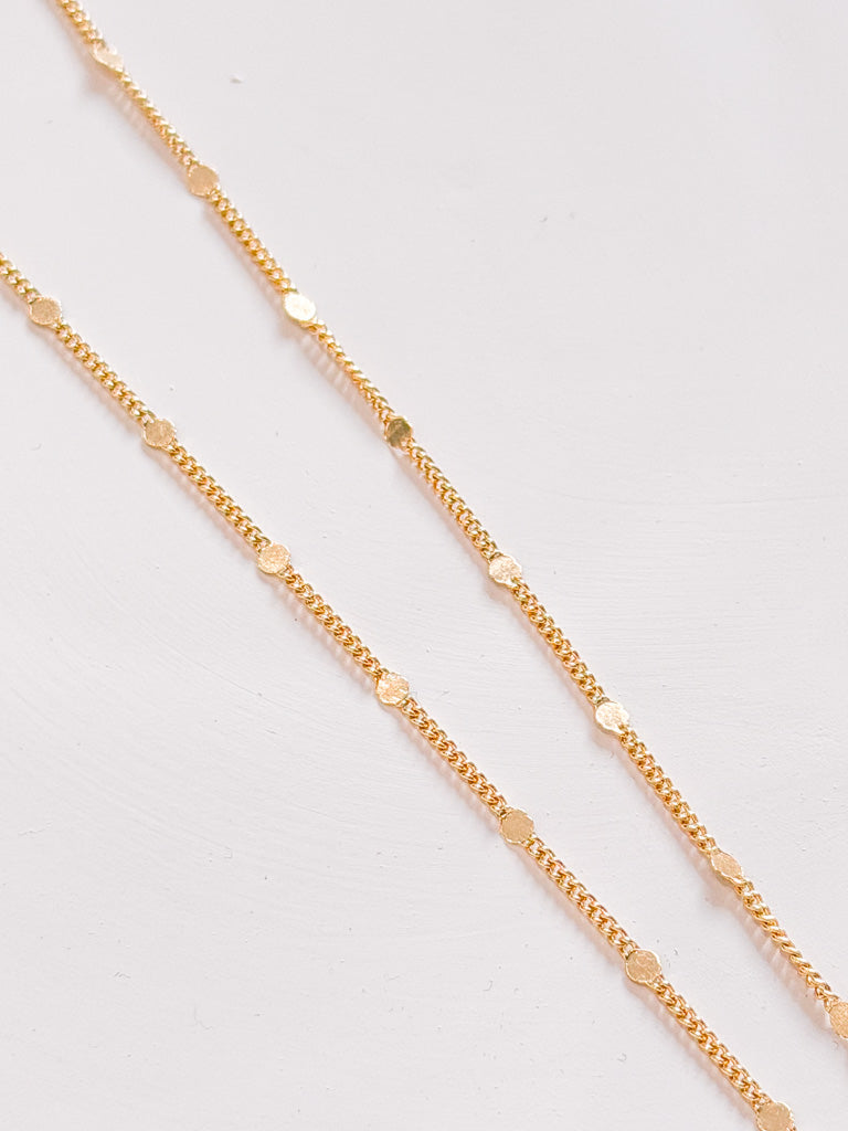 Gold chain necklace on a light gray background