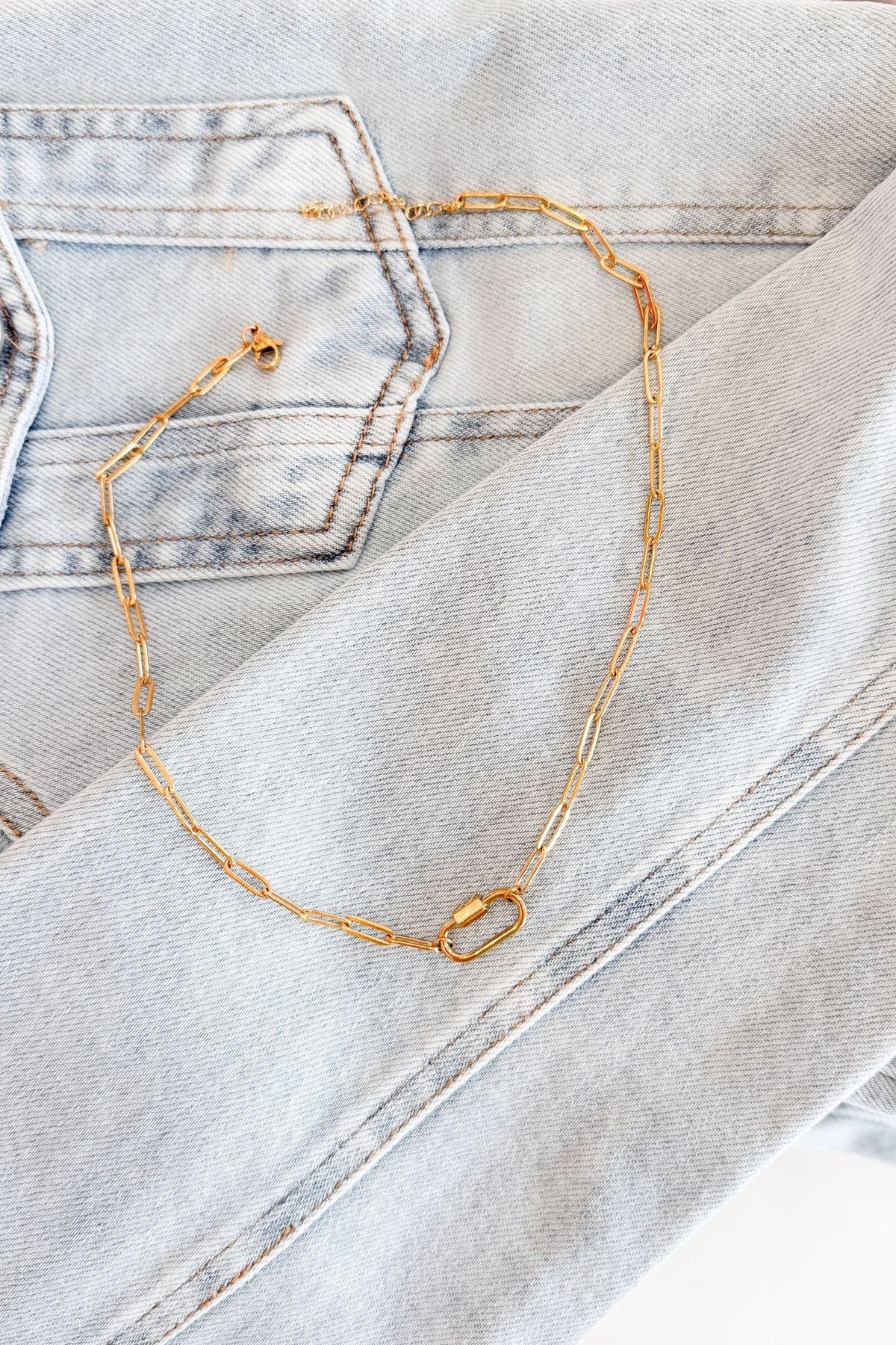 rendy boutique paperclip necklace in gold put on a denim jacket background