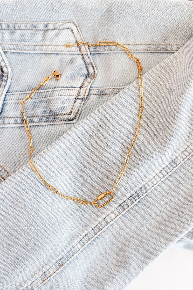 rendy boutique paperclip necklace in gold put on a denim jacket background