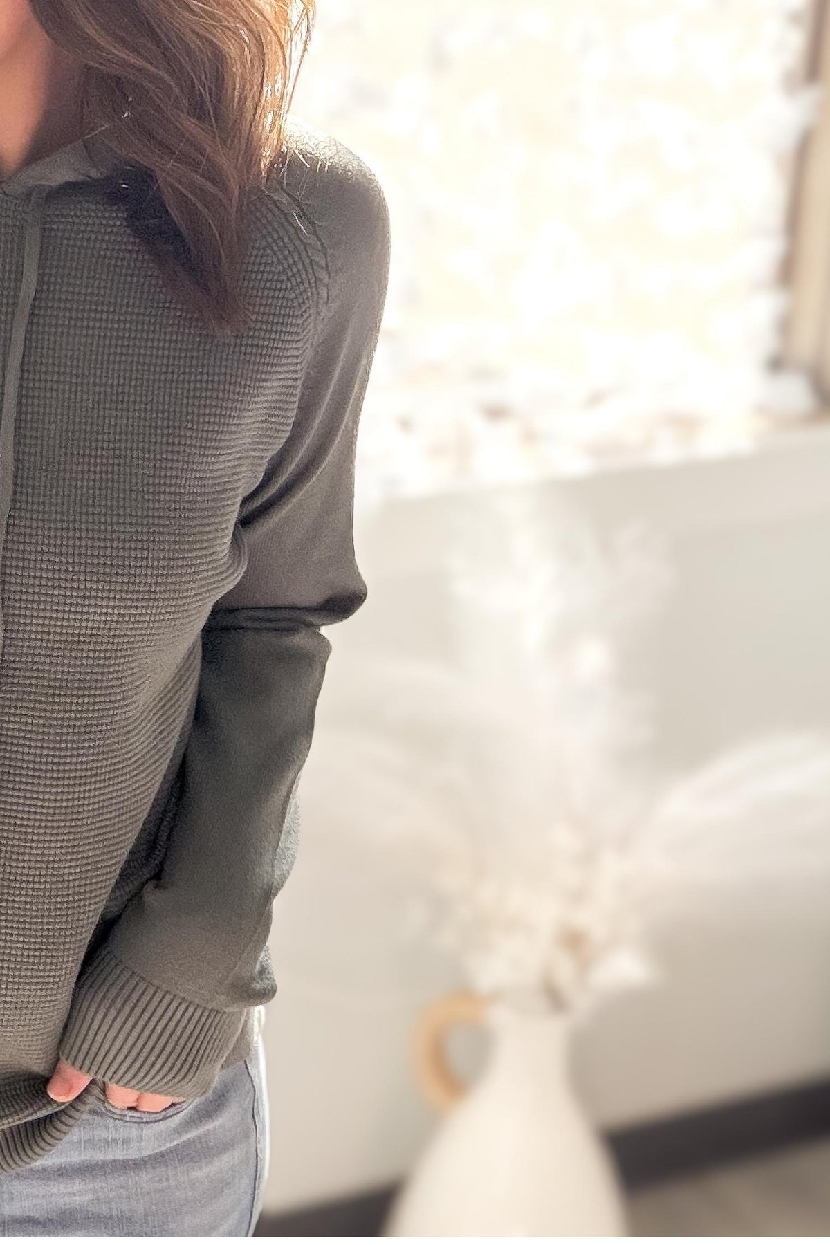 Person wearing a dusty jade sweater in a softly blurred indoor setting