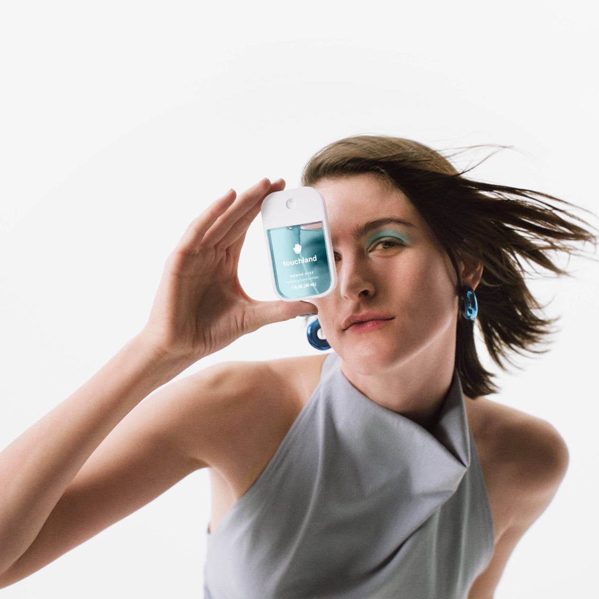 Woman holding a bottle of touchland hand sanitizer product against a white background
