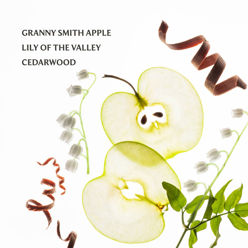 Sliced Granny Smith apple with lily of the valley and cedarwood on a white background