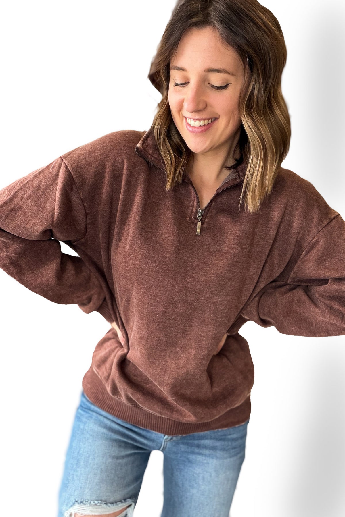 Woman wearing a brown sweater and blue jeans on a white background