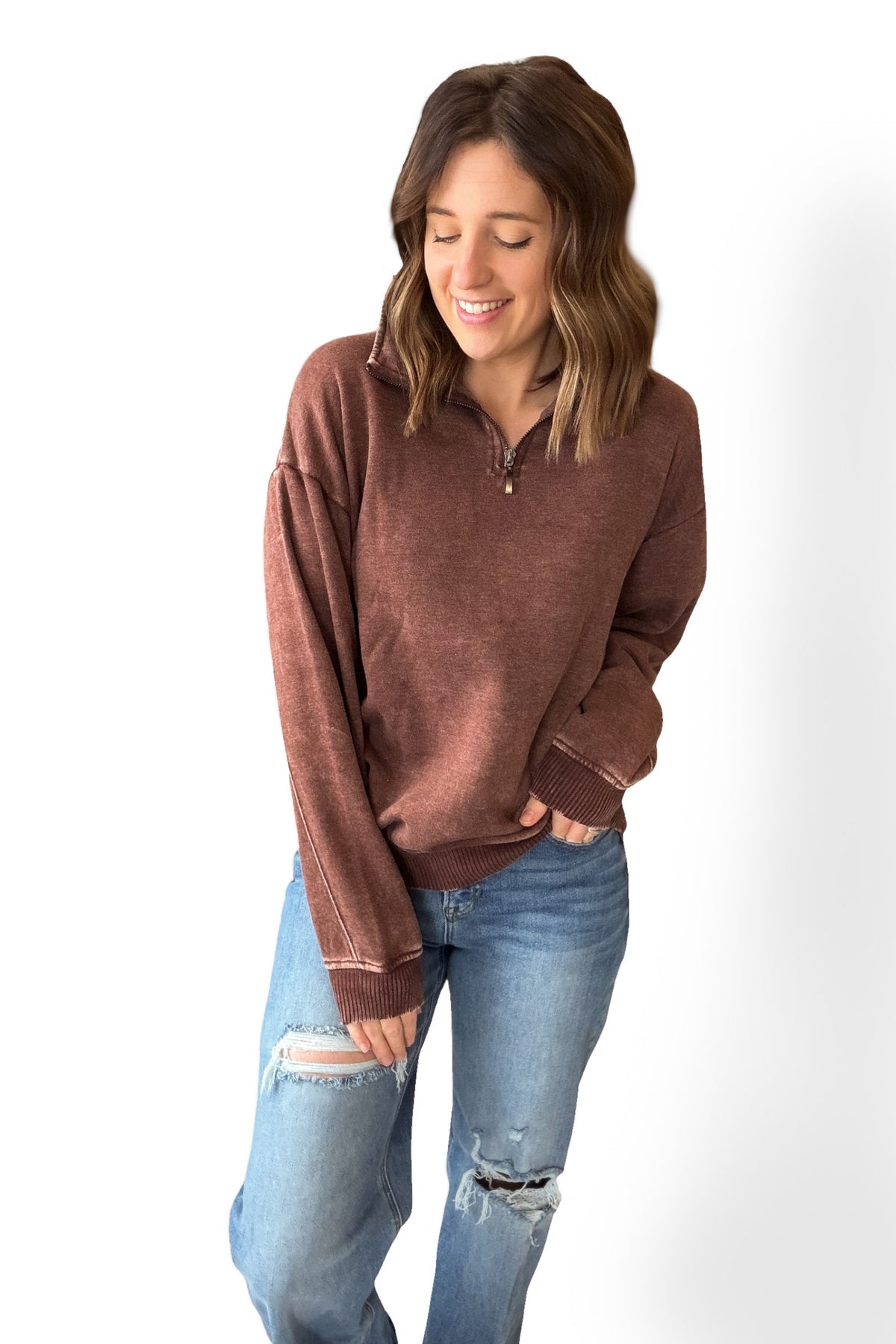 Woman wearing a brown sweater and blue jeans on a white background
