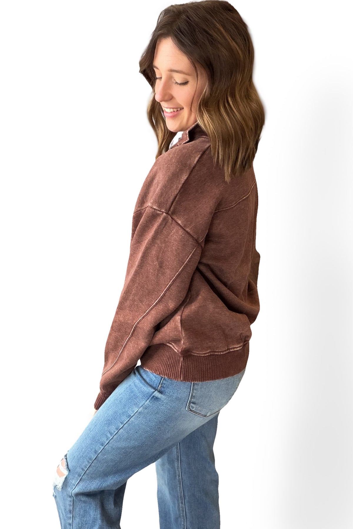 Woman wearing a brown sweater and blue jeans on a white background