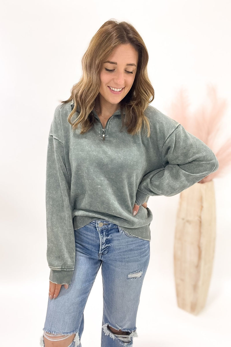 Woman wearing a jade sweatshirt and blue jeans on a white background