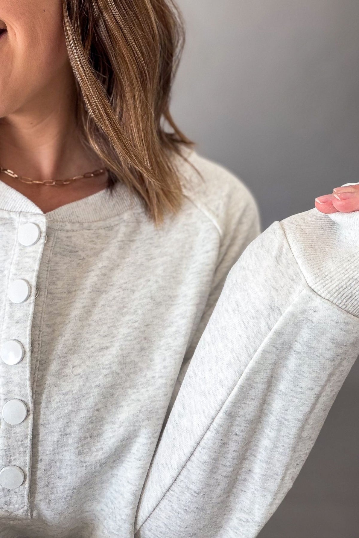 woman showing closeup details of the ash grey snap button pullover