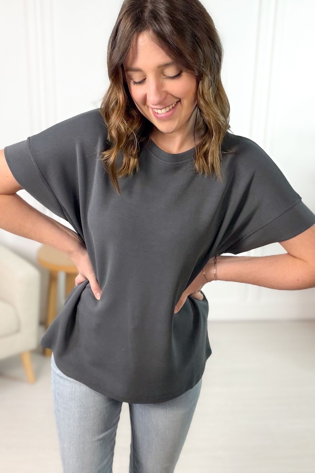 Woman wearing a gray oversized t-shirt and light blue jeans indoors.