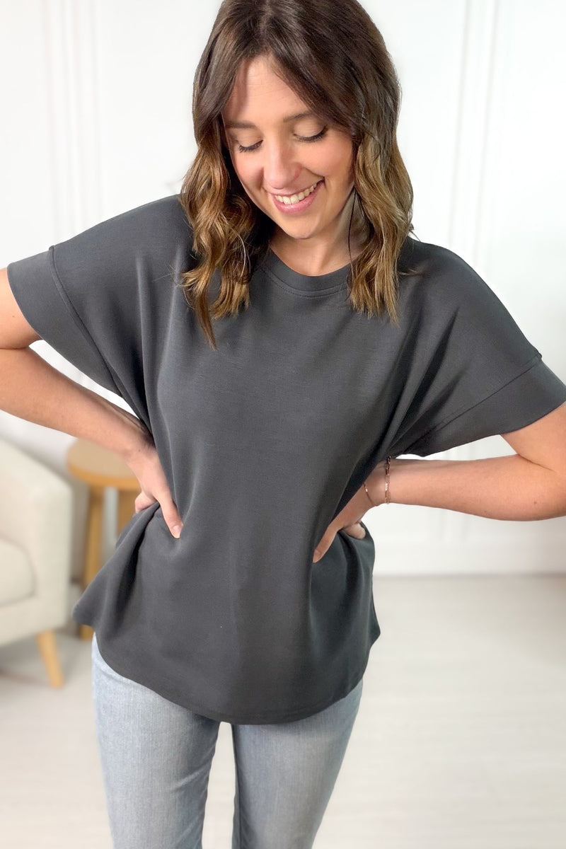 Woman wearing a gray oversized t-shirt and light blue jeans indoors.