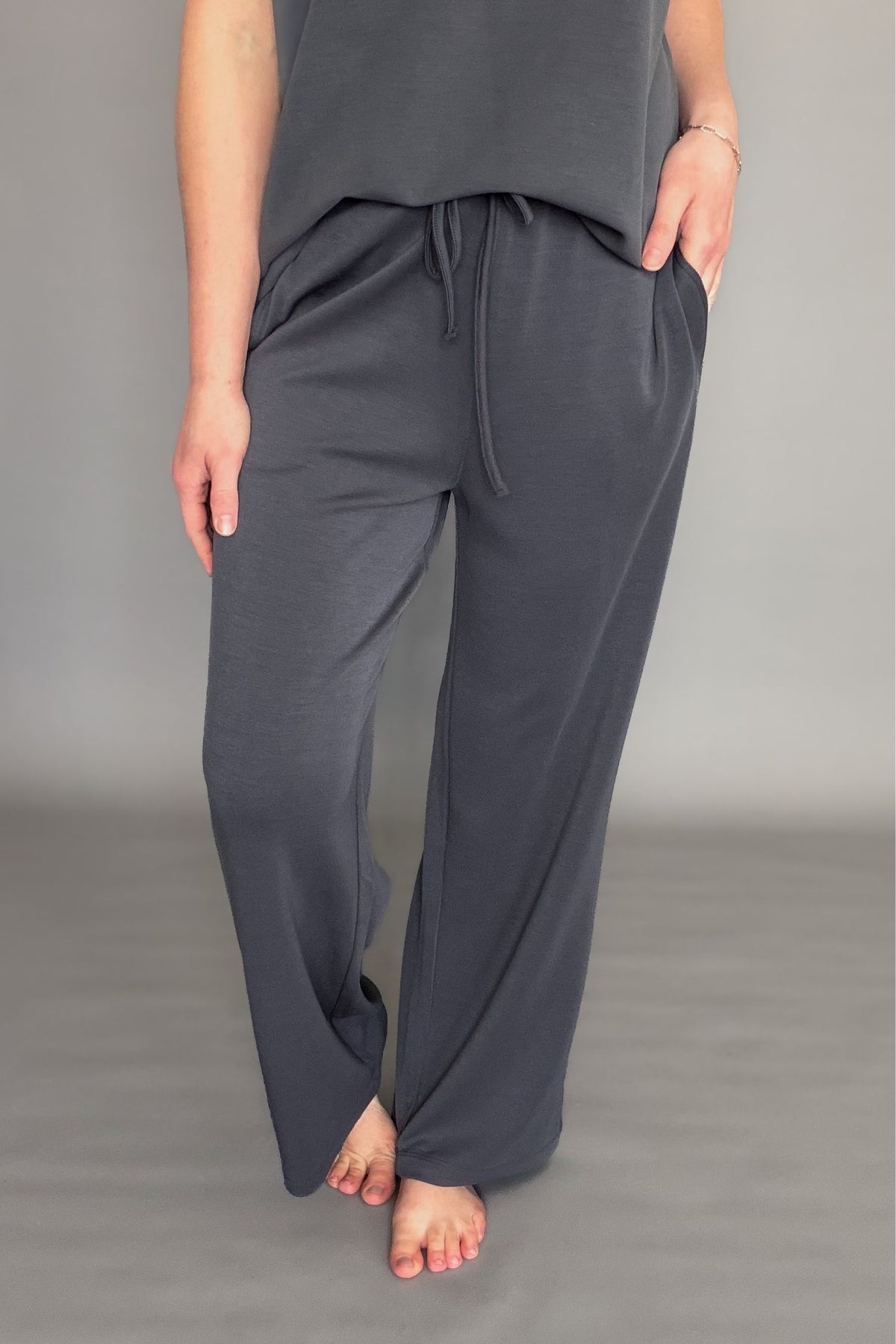 Person wearing gray drawstring pant set on a plain background