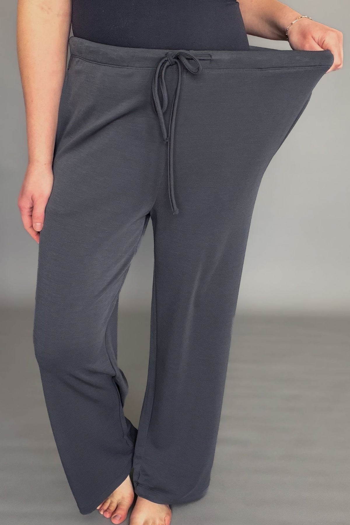 Person wearing gray drawstring pants on a gray background