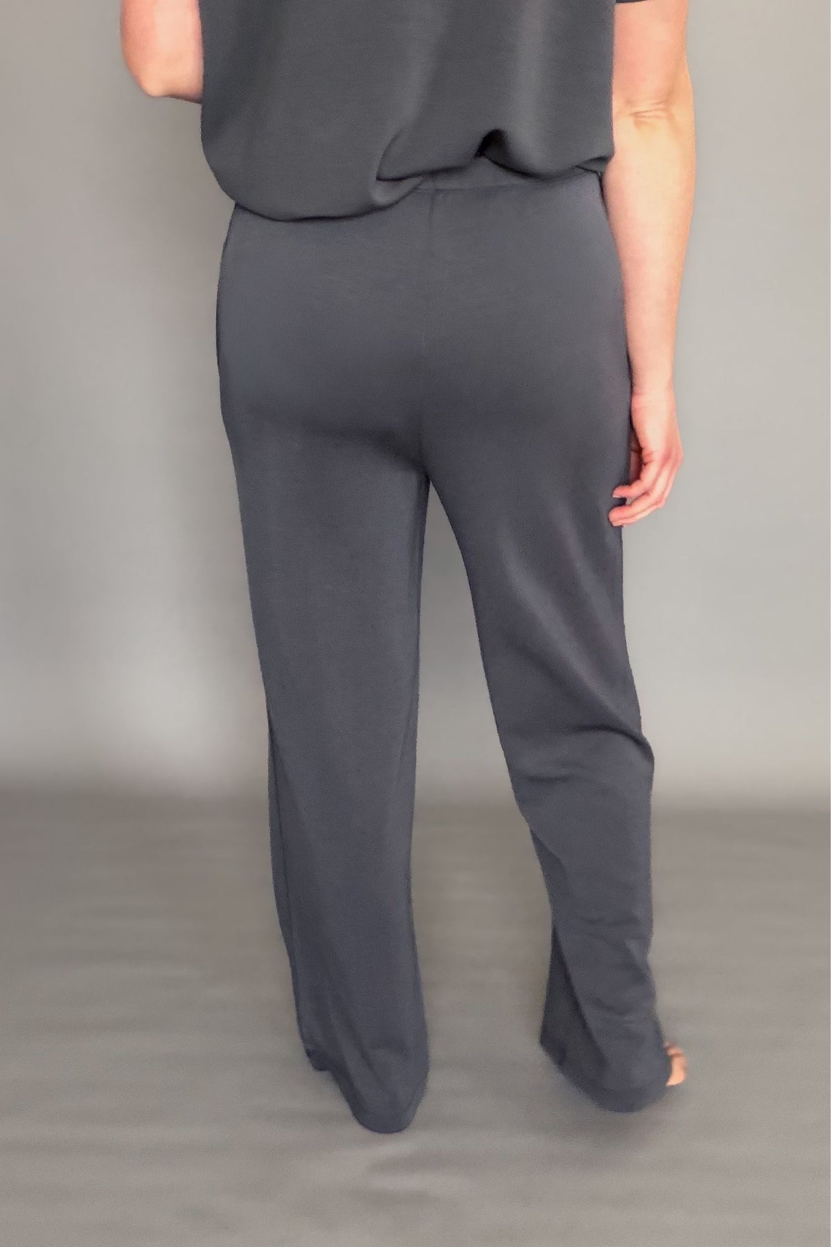 Person wearing gray pant set on a plain background