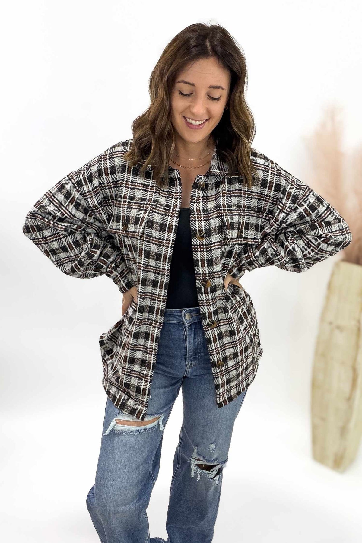 Woman wearing a plaid shirt and ripped jeans on a white background