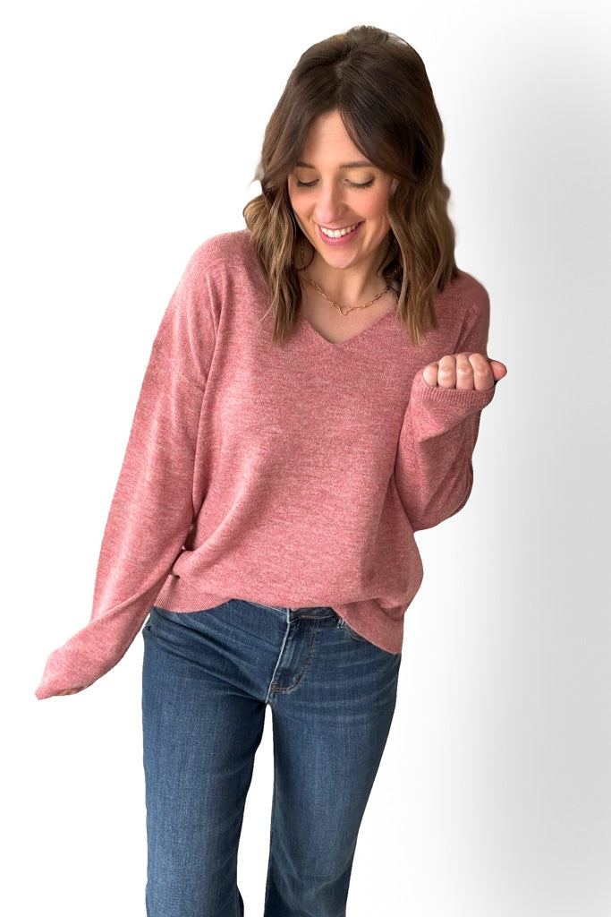 Woman wearing a berry sweater and blue jeans on a white background