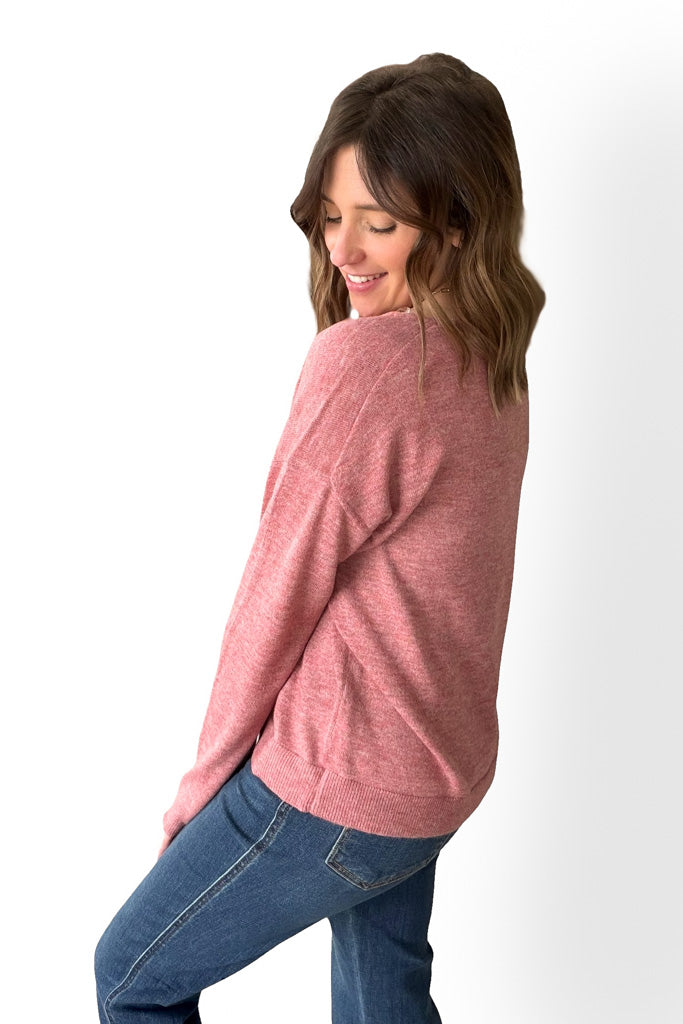 Woman wearing a berry sweater and blue jeans on a white background