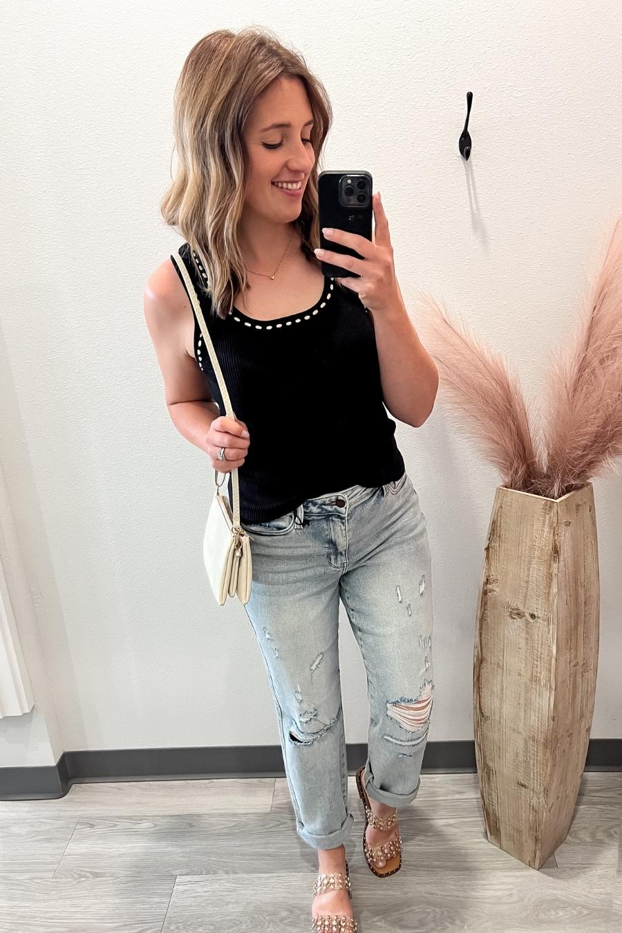 woman taking a selfie in a black tank and jeans