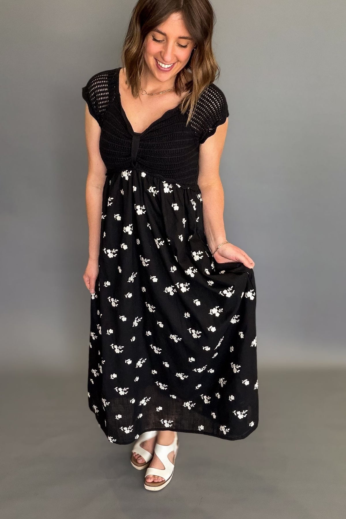 Woman wearing a black crochet top floral midi dress with lined bodice, embroidered skirt, and pockets, flowy black midi dress