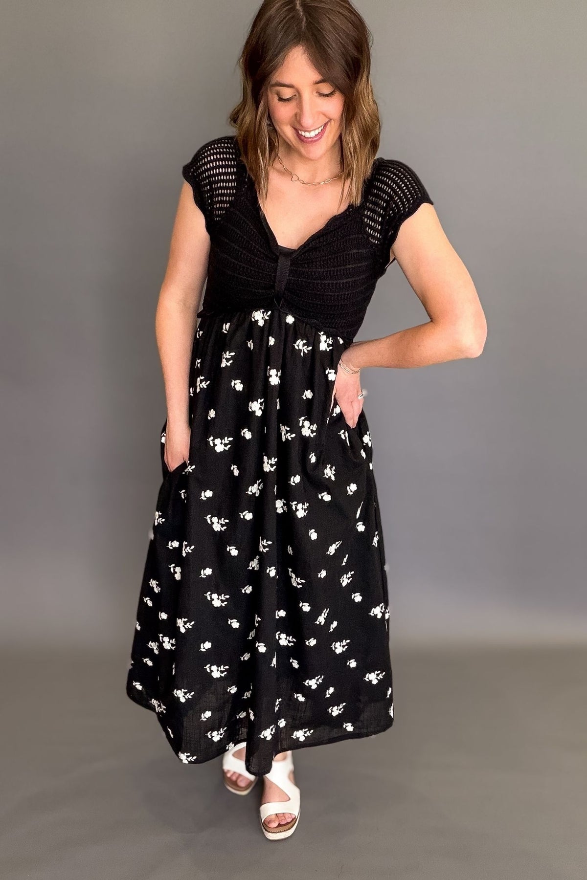 Woman wearing a black crochet top floral midi dress with lined bodice, embroidered skirt, and pockets, flowy black midi dress