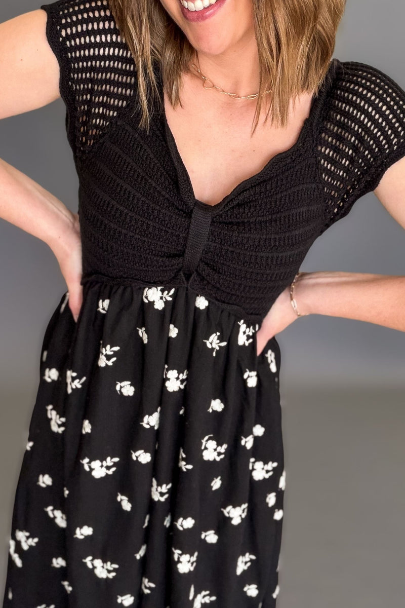 Woman wearing a black crochet top floral midi dress with lined bodice, embroidered skirt, and pockets, flowy black midi dress showing up close details