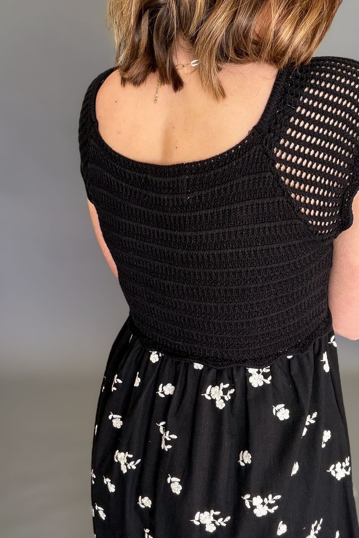 woman wearing a black crochet midi dress showing back details
