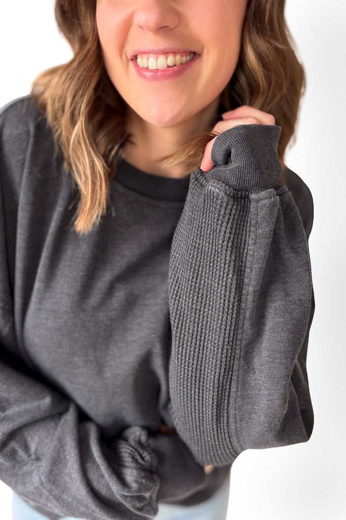 Person wearing a gray sweatshirt with a white background
