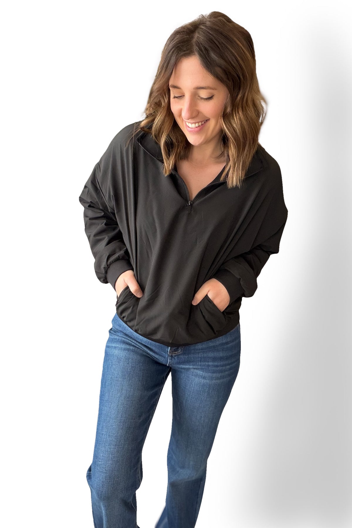 Woman wearing a black long-sleeve top and blue jeans on a white background