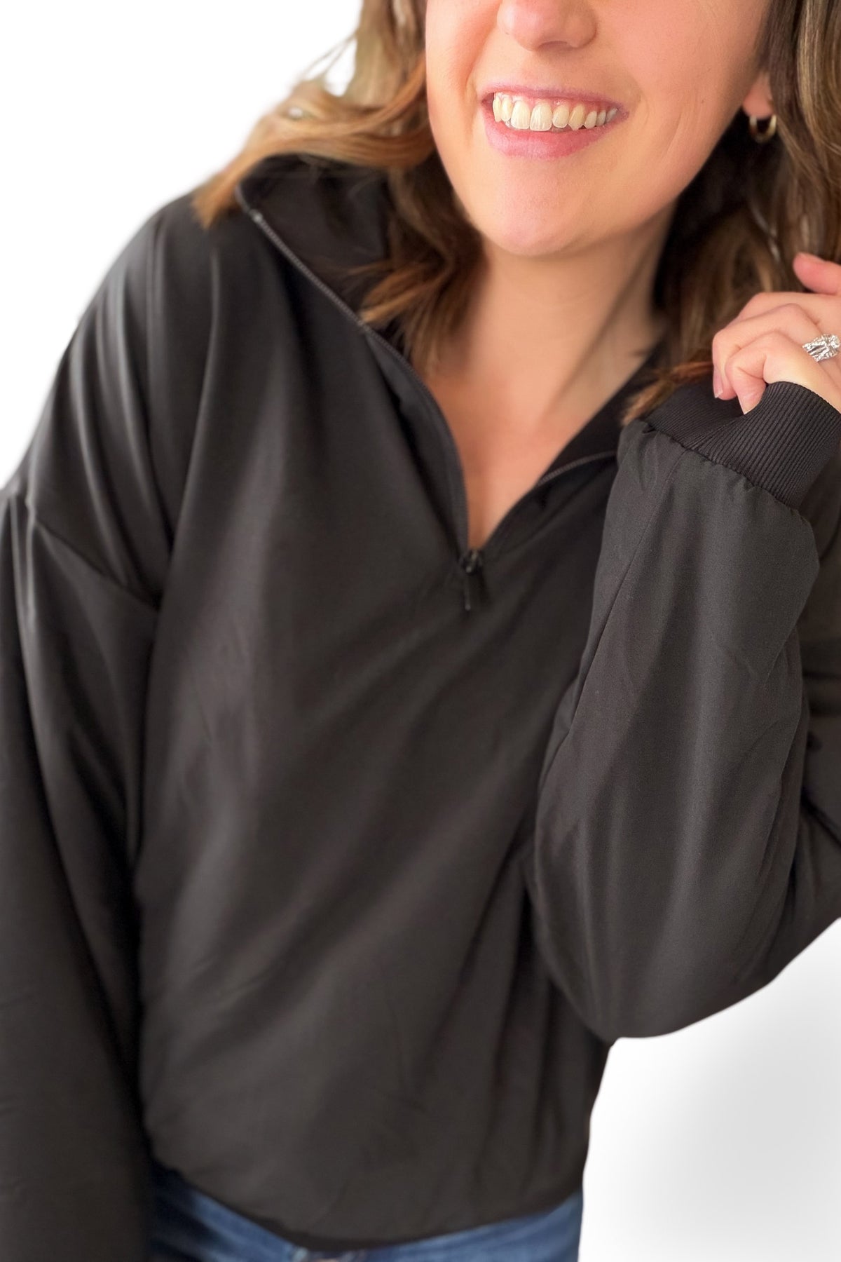 Person wearing a black quarter zip on a white background
