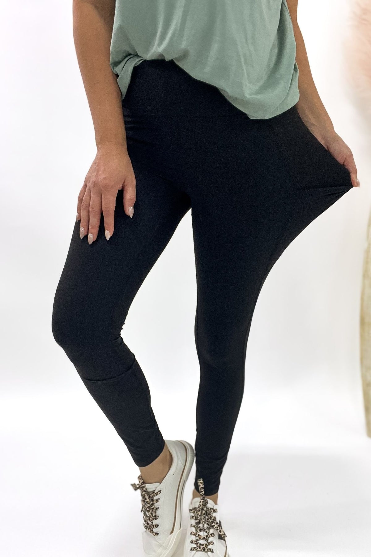 Person wearing black leggings and a light green top on a white background