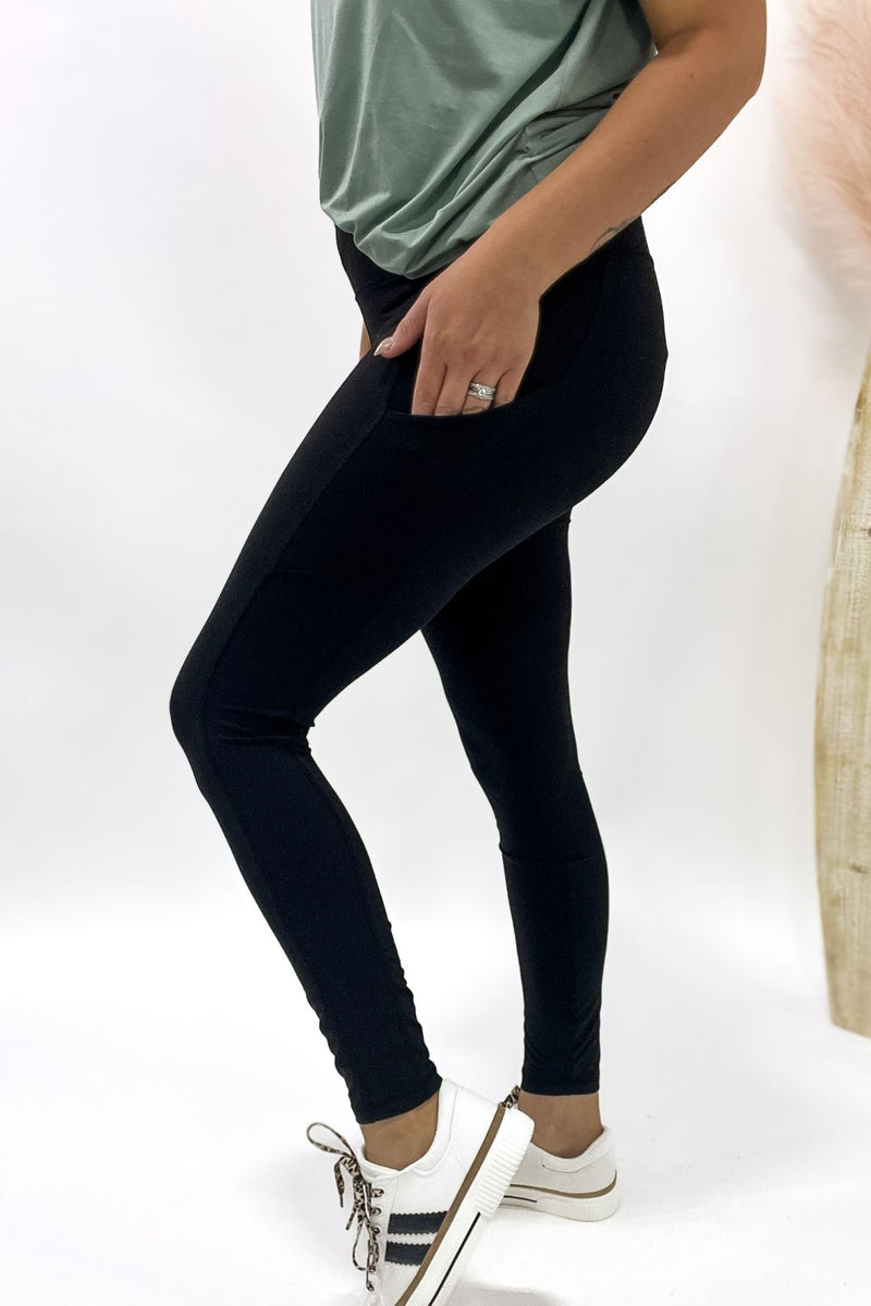 Person wearing black leggings and a green top on a white background