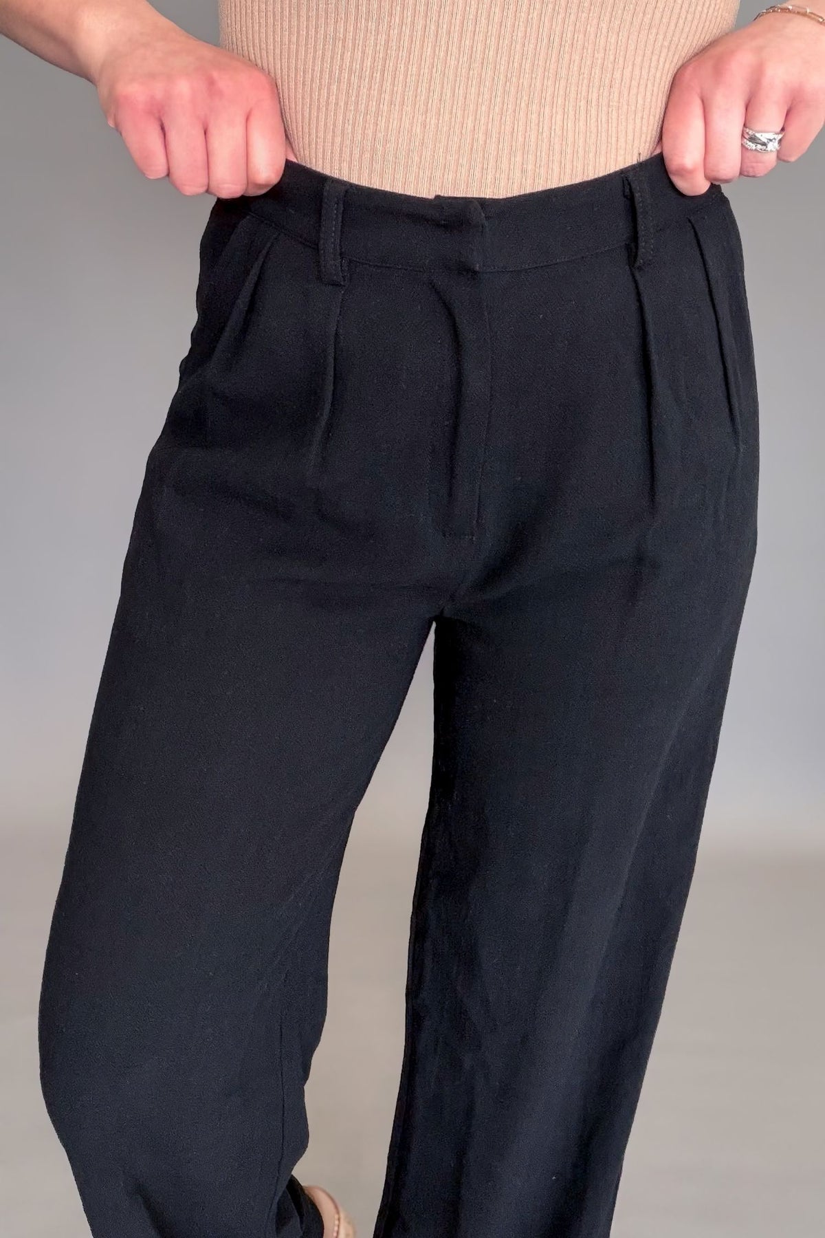 Person wearing black pants with a plain background