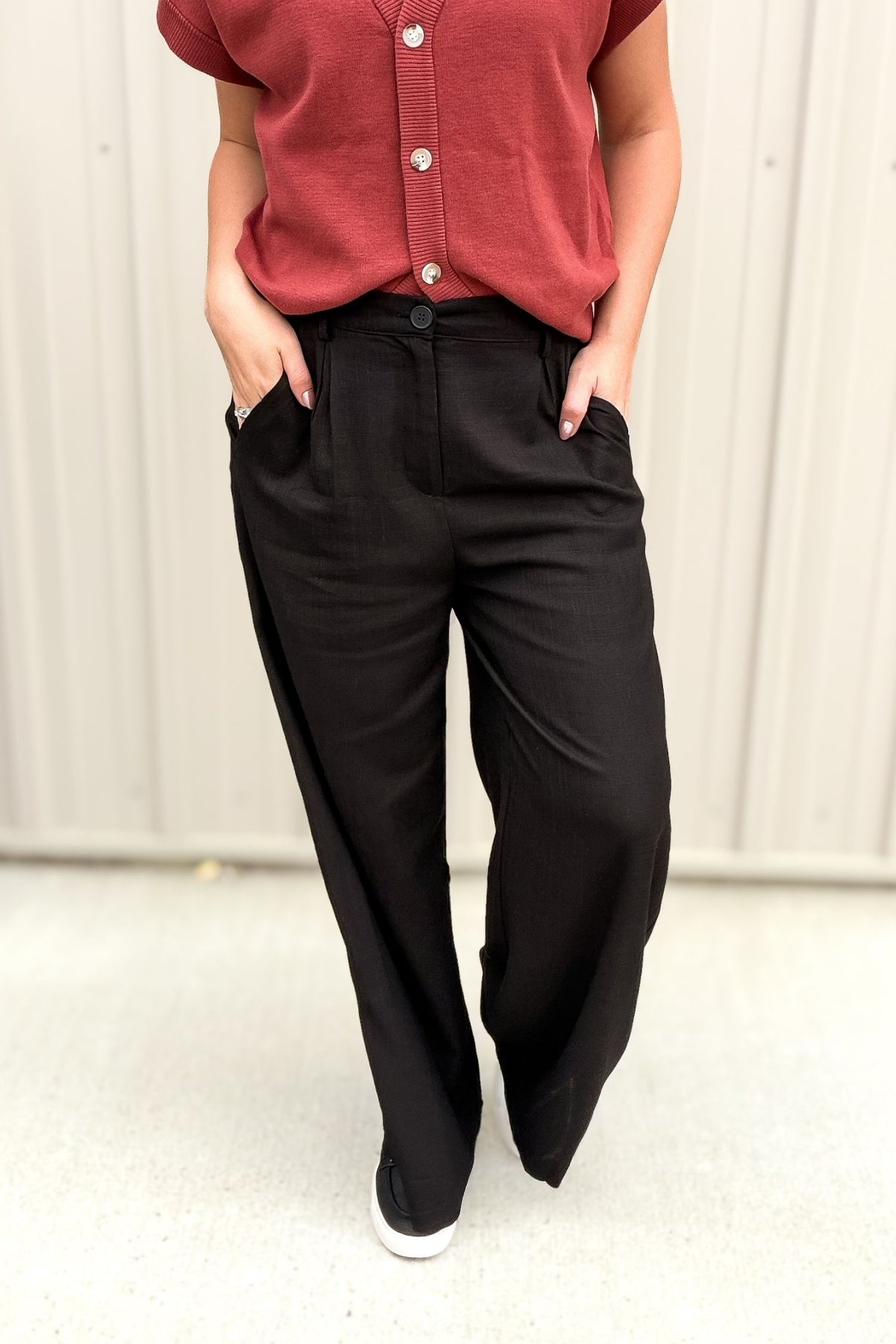 Person wearing a red top and black pants against a white background