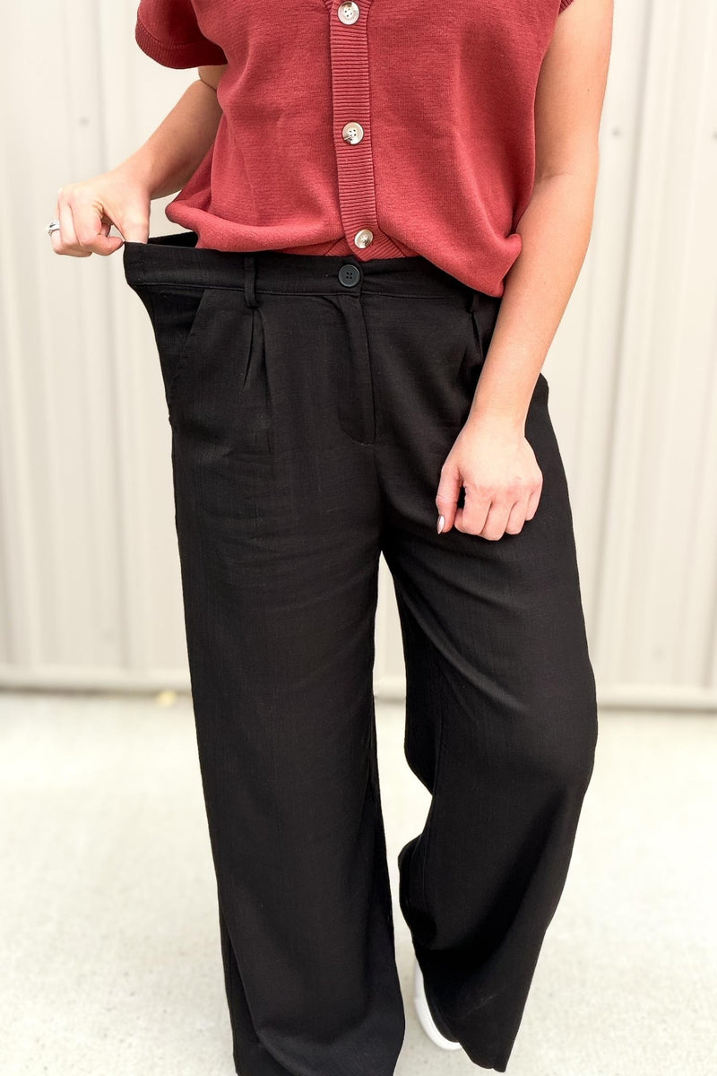 Person wearing a red top and black pants against a neutral background