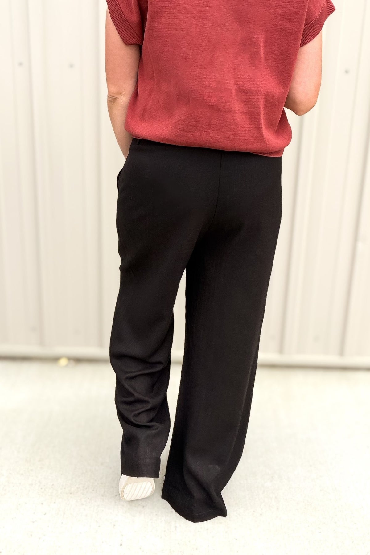 Person wearing a red shirt and black pants on a white background