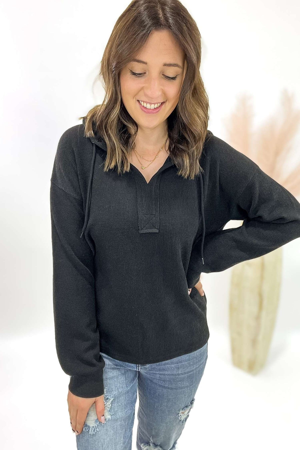 Woman wearing a black long-sleeve shirt and blue jeans on a white background