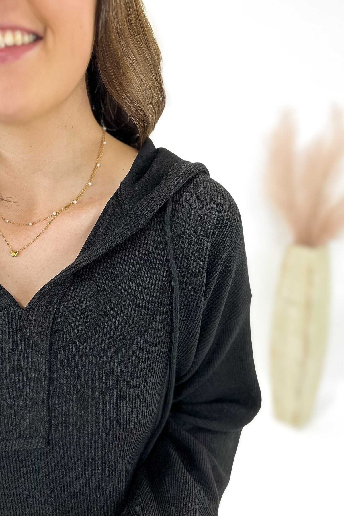 Woman wearing a black ribbed hoodie with a blurred background