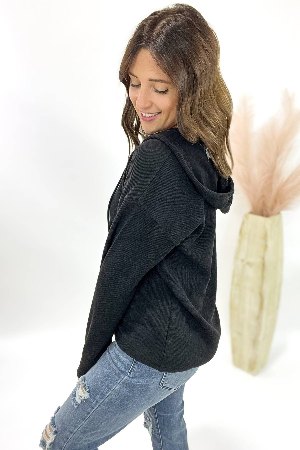 Woman wearing a black hoodie and blue jeans on a white background