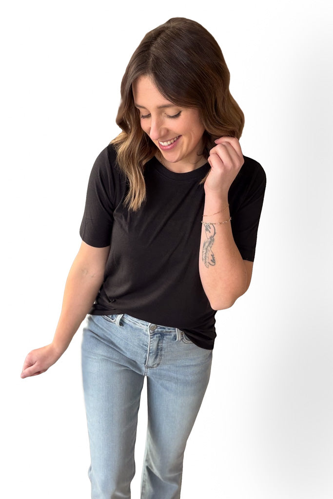Woman wearing a black t-shirt and light blue jeans on a white background